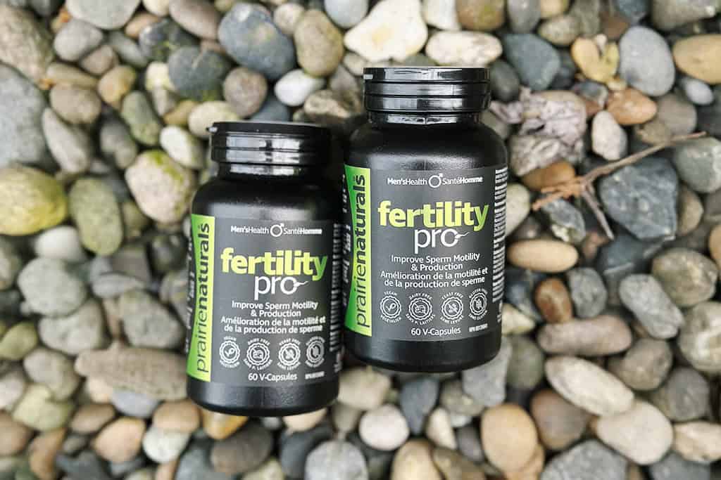 Two bottles of Fertility Pro supplements on a pebble background